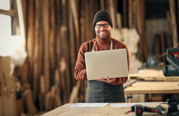 istock Craftsman working with laptop and papers in workshop 1312457789