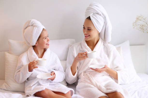 istock Mother and daughter enjoying hot drink on bed 1312457955