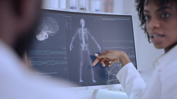 istock African ethnicity doctors working in laboratory. Studying human skeleton and virus models. Discussing 1312459190