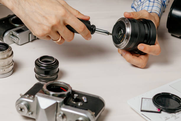 istock Repair of photographic equipment. Engineer - technician engineer disassembling, align and adjusts photo camera lens, optic part. 1312459263