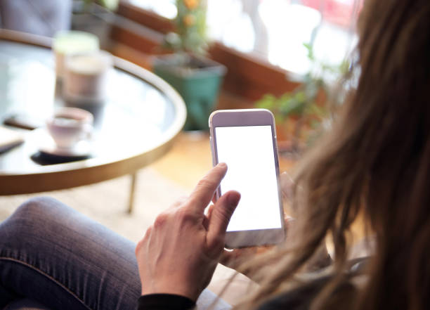 istock Woman using and touching a blank white screen smart phone on a couch 1312459317