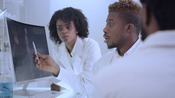 istock African ethnicity doctors working in laboratory. Studying human skeleton and virus models. Discussing 1312460227