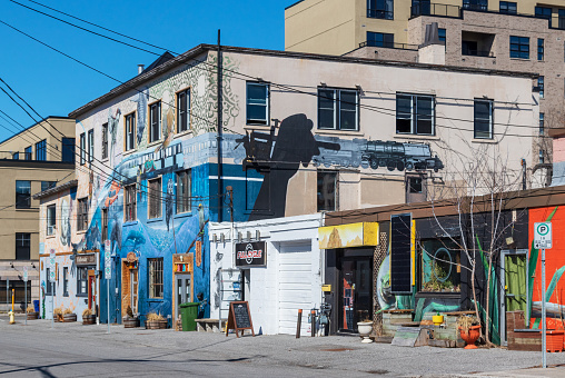Ottawa, Ontario, Canada - March 27, 2020: Several businesses decorated with street art in a trendy urban neighbourhood. Many surrounding buildings have also been spruced up with art.