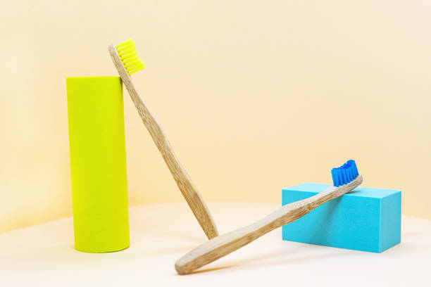 istock Eco-friendly wooden toothbrushes with natural yellow bristles. Abstract composition with podium and column 1312464485
