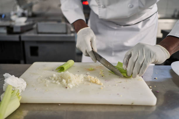 Dedicated Jamaican chef, cutting the onions on a cutting board in his modern commercial kitchen