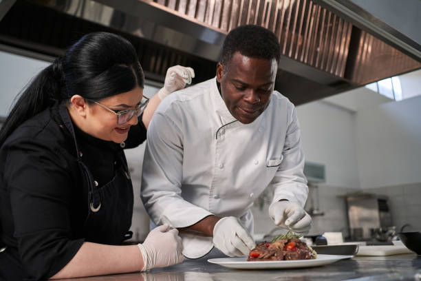 istock Female assistant, observing how her Jamaican chef decorating plate with a dish 1312465332