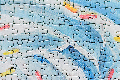 Many light grey and blue textured cardboard puzzle pieces on a table, weekend indoor activity for playing with children at home