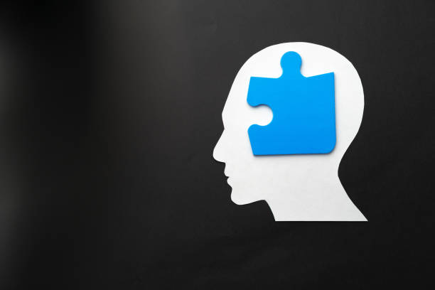 istock Papercut head with jigsaw puzzle pieces on black background 1312466925