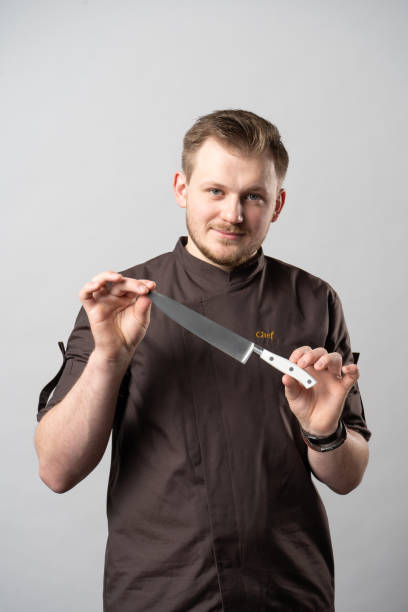istock Chef in a uniform jacket, demonstrates a professional chef's knife 1312467321