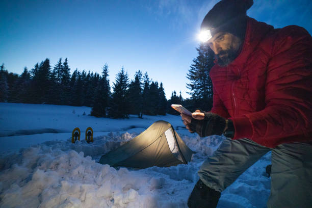 istock Tourist using phone near tent at night while camping in winter mountain. Alone in nature while COVID-19 pandemic. Mental health and life balance. 1312468226
