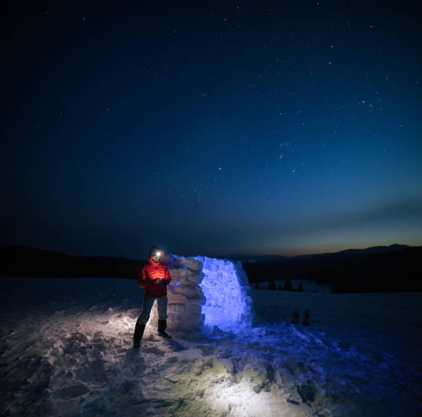 istock Tourist using phone near igloo at night while camping in winter mountain. Alone in nature while COVID-19 pandemic. Mental health and life balance. 1312468233