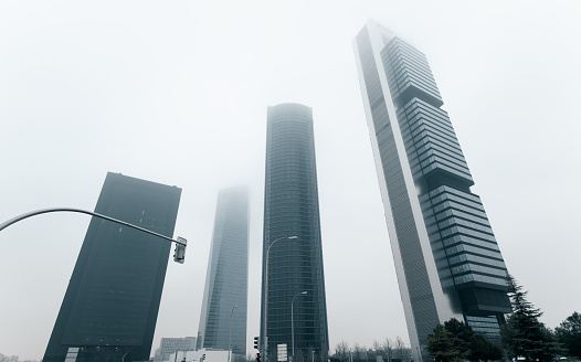 Modern skyscrapers architecture view during foggy weather. Four Towers Business Area against misty sky. Business district located in Paseo de la Castellana in Madrid, Europe, Spain