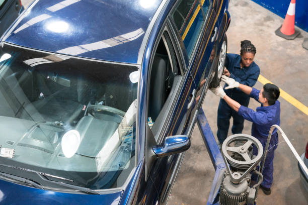Car mechanics at work High angle view of auto mechanics checking car wheel in the auto repair shop. Woman and man at work. car mechanic top view stock pictures, royalty-free photos & images