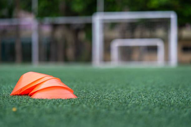 Set of football or soccer training cones on artificial grass turf ground. Sport equipment using to perform speed and ball dribbling practice skill.