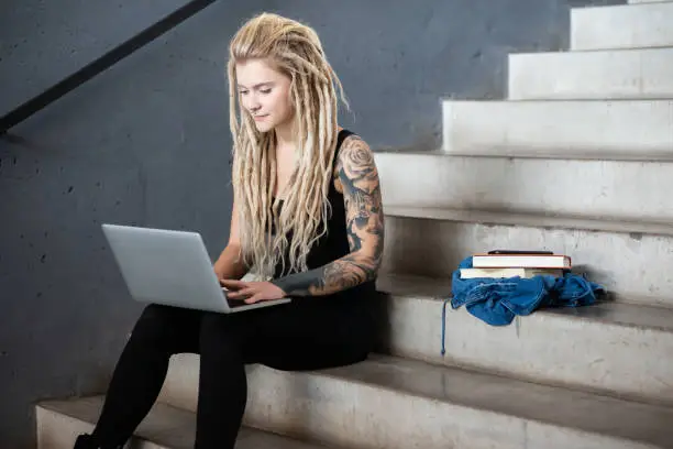 Tattooed woman is working with laptop
