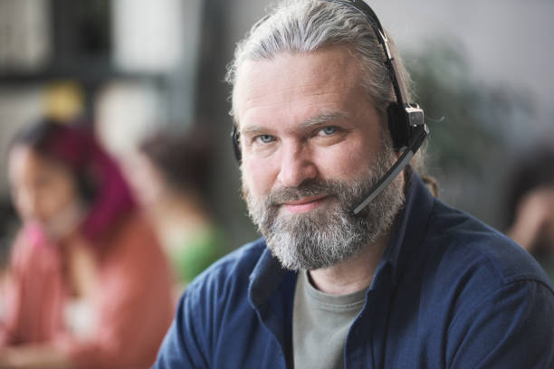 istock Mature call worker in headphones 1312474587