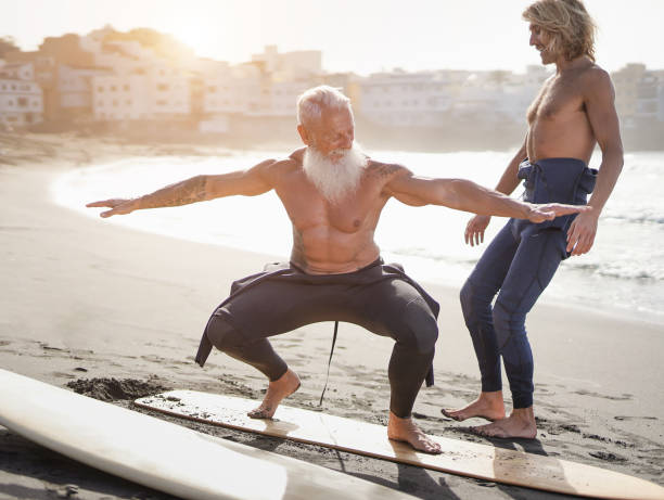 istock Father and son having fun on the beach surfing together - Multi generational men doing extreme sport outdoor 1312474800