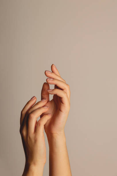 istock Women's hands reach up. With minimalistic manicure on a dark background 1312475252
