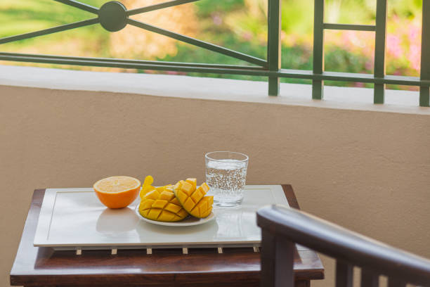 istock Mango cut in half and orange with a cold drink on a tray on the hotel balcony on vacation 1312475285
