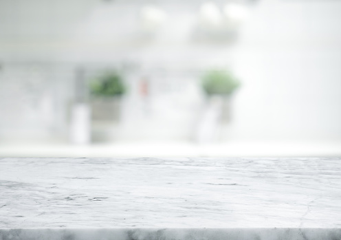 Selective focus.Marble table top on blur white kitchen room background.