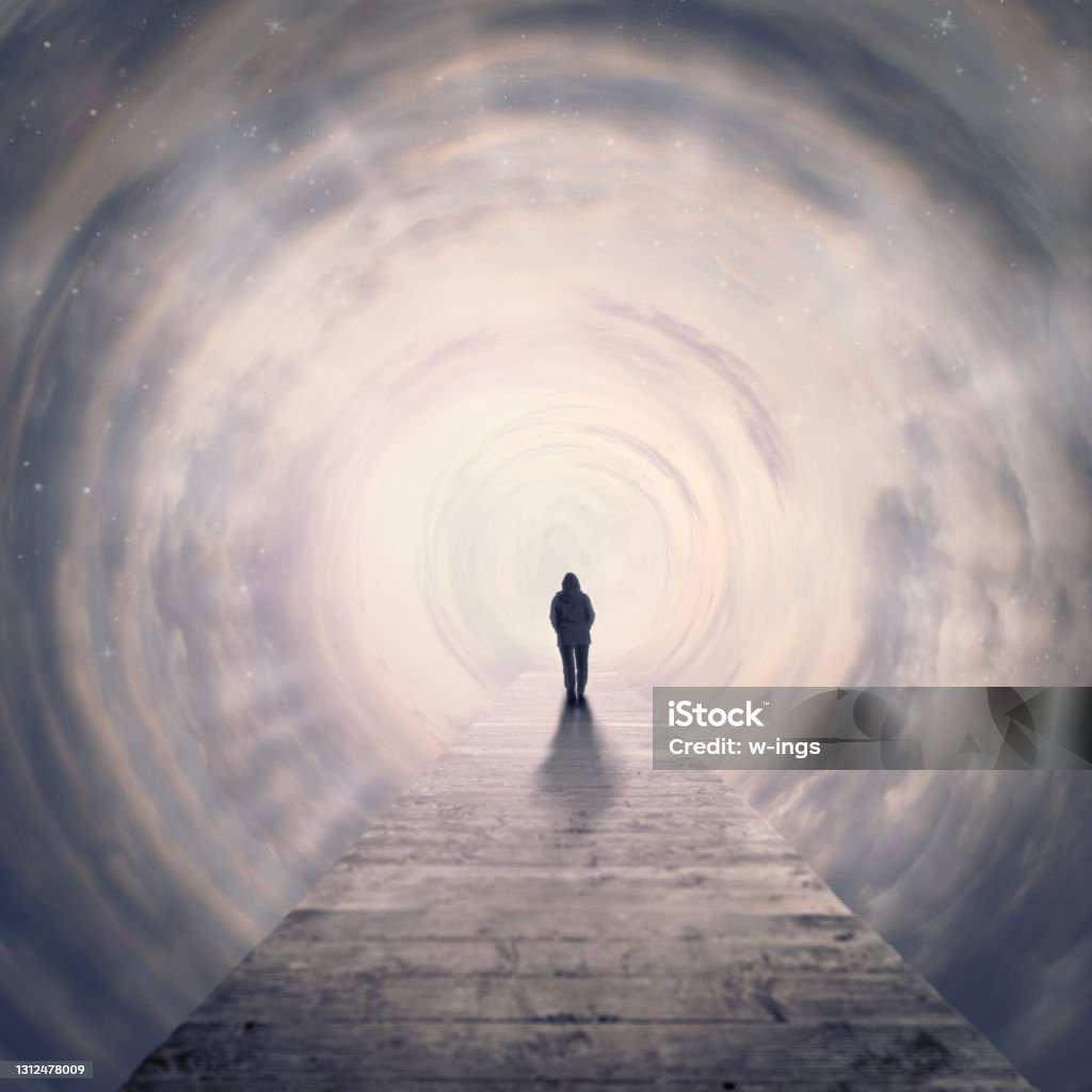 woman walking foreward in tunnel of clouds to the light one woman walking foreward on footbridge in tunnel of clouds into the light Spirituality Stock Photo