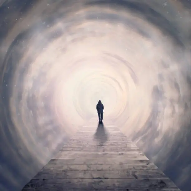 Photo of woman walking foreward in tunnel of clouds to the light