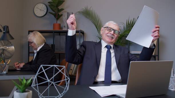 istock Mature elderly man accountant reading documents analyzing financial papers raising hands in surprise 1312478770