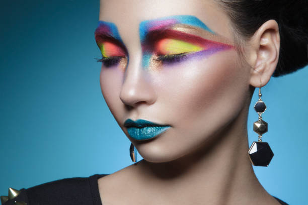 istock Creative makeup. Female model with colored artistic make-up, isolated blue background. 1312478942