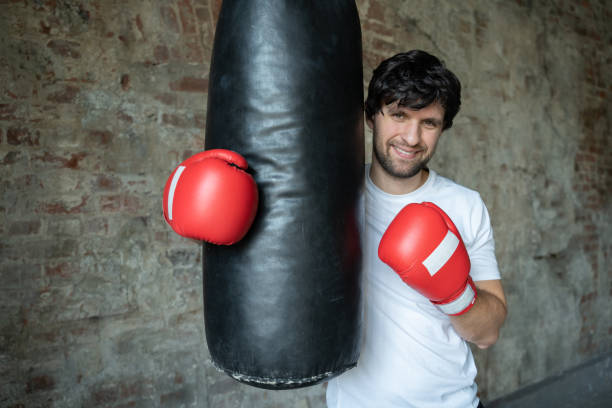 istock Portrait boxing guy posing next to punch bag in gym 1312479262