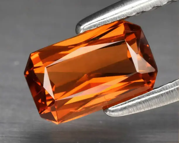 Natural gemstone orange spessartine garnet on a gray background. Spessartite garnet