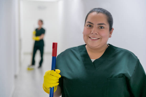 Happy cleaner working at an office building sweeping the floors