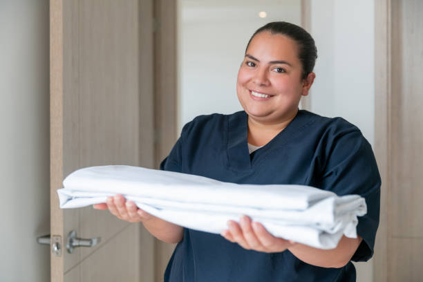 glückliche reinigungskraft, die in einem hotel arbeitet und die handtücher in einem zimmer wechselt - dienstmädchen stock-fotos und bilder