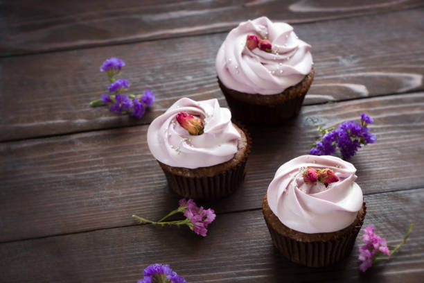 Cupcakes with dried roses, brown wooden board. Cupcakes with roses