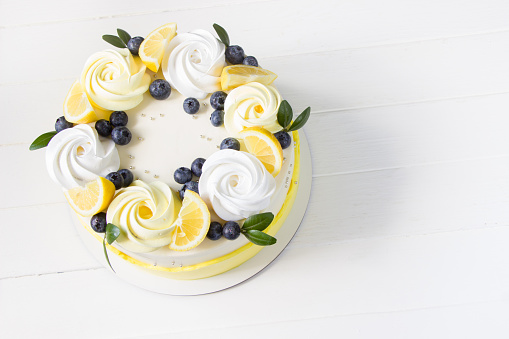 Lemon cake with blueberries and merinques, white background