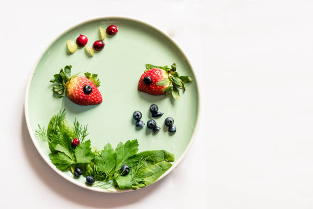 red strawberry in shape of fishes with green vegetable plant, sea world isolated