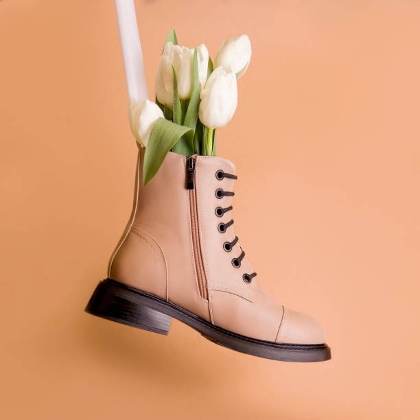 istock Spring boots on a brown background. Beige boots with white tulips 1312485255