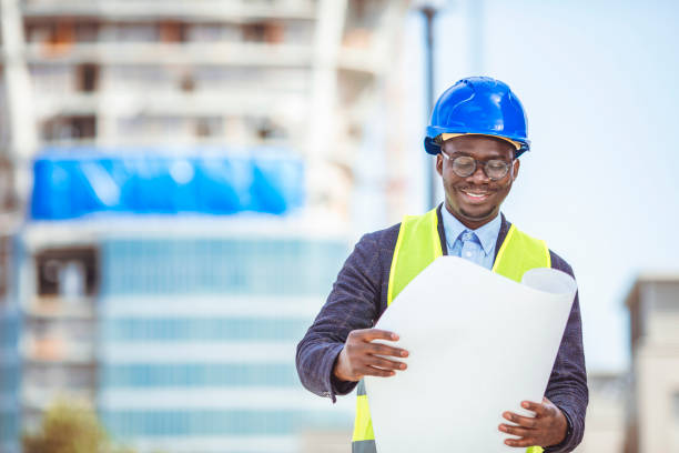 istock Portrait of construction inspector posing with blueprints on building site. 1312489686