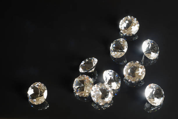 istock Several excellent pure diamonds with reflection on black mirror background close up view. Jewelry diamonds sale, invitation, action, discount banner, poster, card template copy space 1312489839