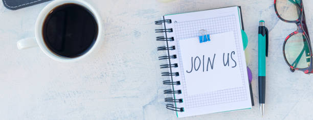 istock banner with Join us. Job recruiting concept. Words Join us in sticker on the working table. Top view 1312491229