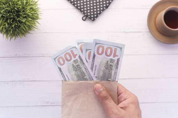 istock person hand putting cash in a envelope. 1312492239