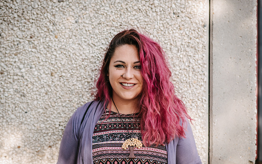 Portrait of a beautiful smiling punk with pink hair and unique style of dressing and tree necklace.