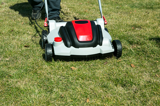 Aeration with a scarifier. Using a scarifier in the garden to improving quality of the lawn in spring. A worker man, Gardener Operating Soil Aeration Machine on Grass Lawn.