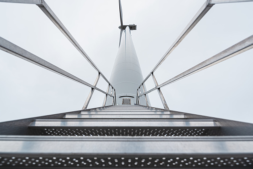 Low angle of metal stairs leading to a wind turbine access door.