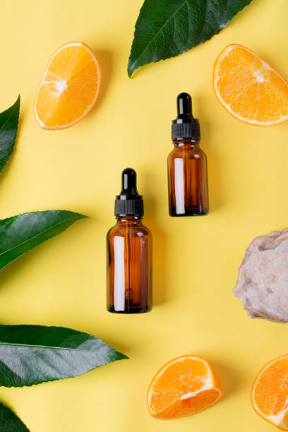 istock Serum bottles, orange fruit, palm leaf and stone on yellow 1312502854
