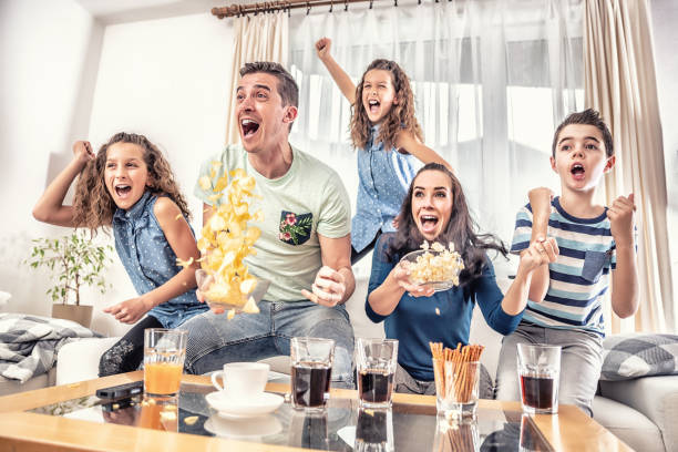 aficionados delirantes animando los deportes, como la familia de cinco personas ven fútbol, o partido de hockey sobre hielo en la televisión en casa, gritando de alegría. - family television watching watching tv fotografías e imágenes de stock