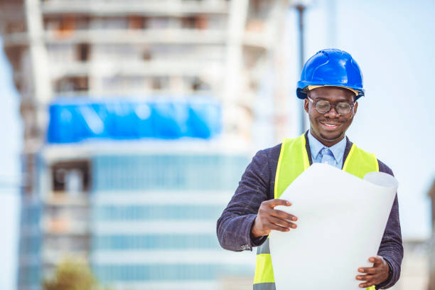 istock Portrait of construction inspector posing with blueprints on building site. 1312504657