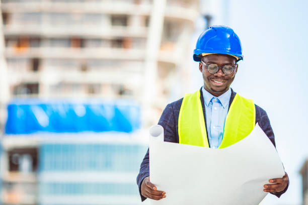 istock Smiling businessman with helmet on head standing in building in construction process and checking on works 1312504709