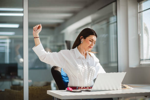 istock Young businesswoman with eyes closed stretching while working at her office desk 1312508700