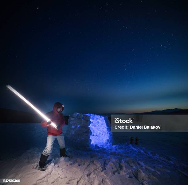 Jedi Concept Tourist Using Light Near Igloo At Night While Camping In Winter Mountain Alone In Nature While Covid19 Pandemic Mental Health And Life Balance Stock Photo - Download Image Now