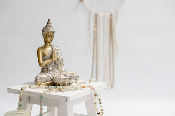 Mediation - golden Budda stands on a small stool. There is a prayer chain next to the budda. In the background is a dream catcher
